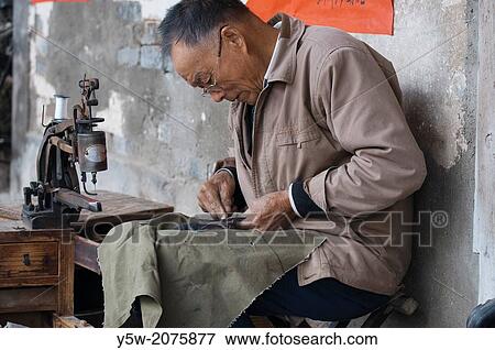 Stock Photo - Shoe repairer at work in Tangmo heritage village, Huizhou, Anhui, China.. Fotosearch