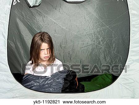 Stock Image - Shot of a Young Girl looking Unhappy in her Tent. Fotosearch