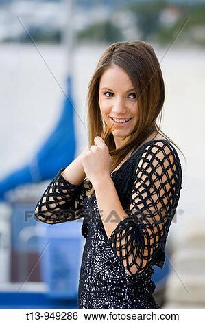 Shy young woman with a patch of hair in her hand in front of small ship in harbour View Large Photo Image Stock Photograph - Shy young woman with a patch of hair in her hand in front of small ship in harbour. Fotosearch