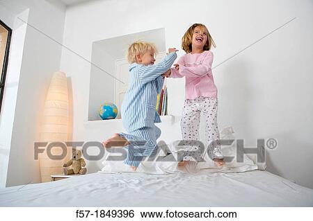 Siblings jumping on the bed View Large Photo Image Stock Photograph - Siblings jumping on the bed. Fotosearch