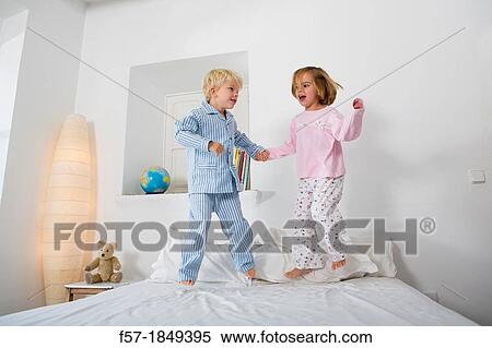 Siblings jumping on the bed View Large Photo Image Stock Photography - Siblings jumping on the bed. Fotosearch