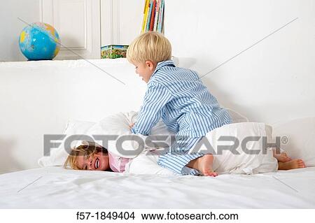 Picture - Siblings playing on their bed. Fotosearch