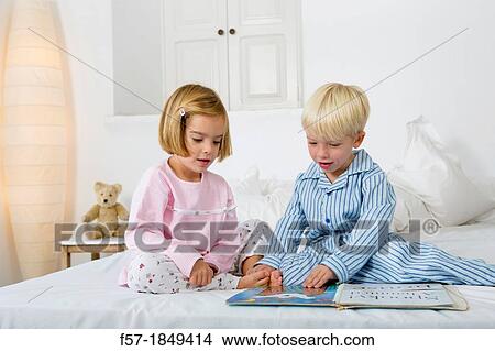Siblings reading a book in their pyjamas View Large Photo Image Picture - Siblings reading a book in their pyjamas. Fotosearch