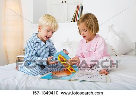 Siblings reading a book in their pyjamas View Large Photo Image Stock Image - Siblings reading a book in their pyjamas. Fotosearch