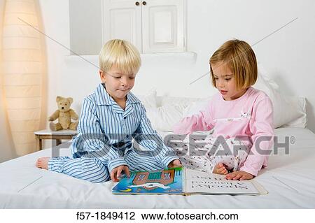 Siblings reading a book in their pyjamas View Large Photo Image Stock Image - Siblings reading a book in their pyjamas. Fotosearch