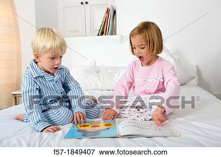 Siblings reading a book in their pyjamas View Large Photo Image Stock Photo - Siblings reading a book in their pyjamas. Fotosearch