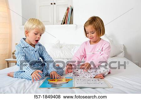 Siblings reading a book in their pyjamas View Large Photo Image Stock Photo - Siblings reading a book in their pyjamas. Fotosearch