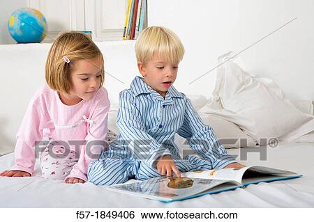 Siblings reading a book in their pyjamas View Large Photo Image Stock Photograph - Siblings reading a book in their pyjamas. Fotosearch