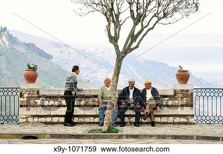 Stock Photo - Sicily, Italy Men chatting in the square of the village of Castel Mola near Taormina. Fotosearch
