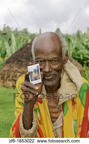 Sidama Tribe Ethiopia Africa old man age 82 with his hut home and holding new Fuji Polaroid photo print 30 View Large Photo Image Stock Image - Sidama Tribe Ethiopia Africa old man age 82 with his hut home and holding new Fuji Polaroid photo print 30. Fotosearch