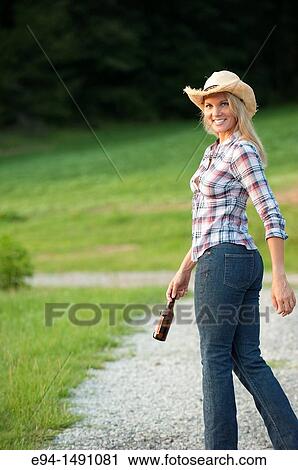 Side view of a blond woman wearing blue jeans and a straw hat waliking on a country path looking back at the camera. View Large Photo Image Stock Image - Side view of a blond woman wearing blue jeans and a straw hat waliking on a country path looking back at the camera.. Fotosearch