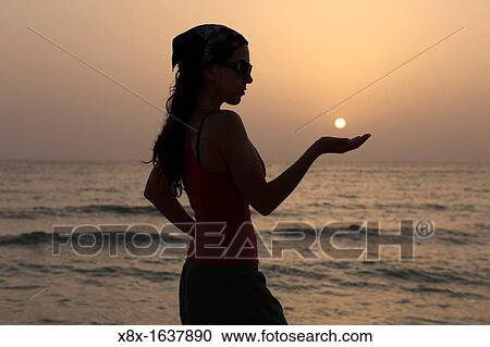 Sihouette of a woman holding the sun View Large Photo Image Stock Image - Sihouette of a woman holding the sun. Fotosearch