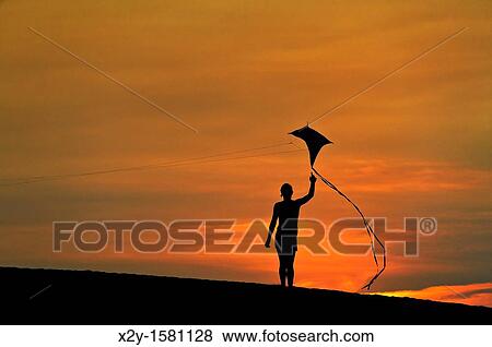 Silhouette of a child flying a kite View Large Photo Image Stock Photo - Silhouette of a child flying a kite. Fotosearch