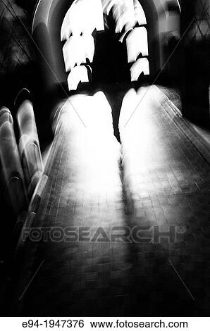 Stock Photograph - Silhouette of a distorted human figure in the center aisle of a church, black & white.. Fotosearch