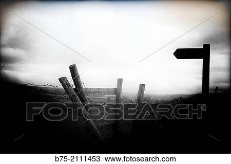 Stock Image - Silhouette of a signal post indicating a foothpath in Yorkshire Dales, England, UK, Europe.. Fotosearch