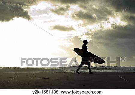 Silhouette of a surfer walking with his surfboard along the beach with stormy clouds in the background, Tarifa, Andalucia, Spain View Large Photo Image Stock Photo - Silhouette of a surfer walking with his surfboard along the beach with stormy clouds in the background, Tarifa, Andalucia, Spain. Fotosearch