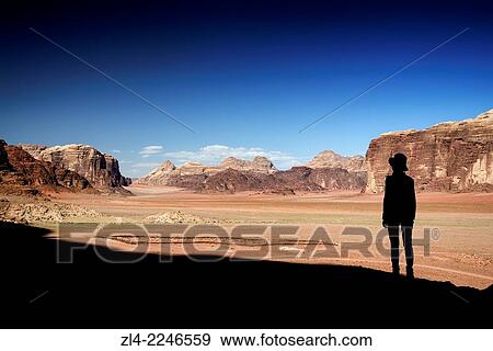 Stock Photo - Silhouette of a woman and red sand desert from Jebel Qattar. Jordan, Wadi Rum desert, protected area inscribed on UNESCO World Heritage list. Model Released.. Fotosearch