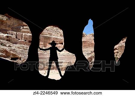 Stock Photo - Silhouette of a woman at the entrance of a cave near the theatre. Jordan (Hashemite Kingdom of), Ma'an Governorate (Maan), ancient city of Petra. Model Released.. Fotosearch