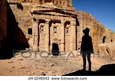 Stock Image - Silhouette of a woman watching the fa? ade of the Roman Soldier's Tomb, carved out of a sandstone rock face. Jordan (Hashemite Kingdom of), Ma'an Governorate (Maan), ancient city of Petra. Model Released.. Fotosearch