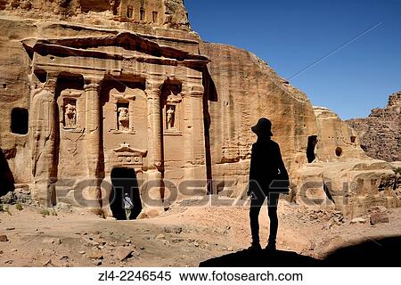 Stock Photography - Silhouette of a woman watching the fa? ade of the Roman Soldier's Tomb, carved out of a sandstone rock face. Jordan (Hashemite Kingdom of), Ma'an Governorate (Maan), ancient city of Petra. Model Released.. Fotosearch
