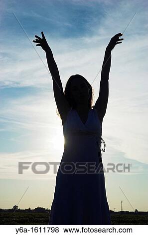 Silhouette of a young woman at dusk, arms raised View Large Photo Image Stock Photo - Silhouette of a young woman at dusk, arms raised. Fotosearch