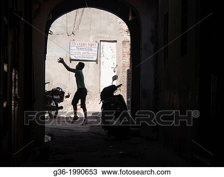 Stock Image - Silhouette of boy playing in front of an education center in Jaipur, Rajasthan, India.. Fotosearch
