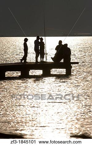 Stock Image - Silhouette of children fishing on a gangway. Fotosearch