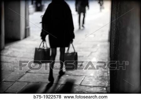 silhouette of lady walking back down the street with bags in hand View Large Photo Image Stock Photo - silhouette of lady walking back down the street with bags in hand. Fotosearch