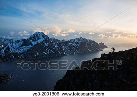 Silhouette of landscape photographer on summit of Offersoykammen with Flakstadoy in background, Lofoten Islands, Norway. View Large Photo Image Stock Photograph - Silhouette of landscape photographer on summit of Offersoykammen with Flakstadoy in background, Lofoten Islands, Norway.. Fotosearch