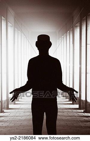 Silhouette of man with hat standing in backlit colonnade showing his hands. Conceptual image of magic, mystery and the paranormal. View Large Photo Image Picture - Silhouette of man with hat standing in backlit colonnade showing his hands. Conceptual image of magic, mystery and the paranormal.. Fotosearch