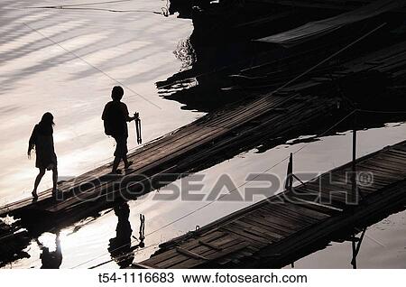 Stock Image - Silhouette of two people, who go over a bridge. Fotosearch
