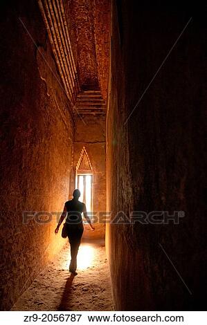 Stock Photo - Silhouette of woman walking toward narrow window in a dark ancient temple.. Fotosearch