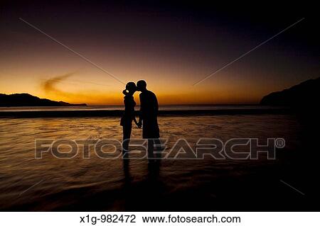 Stock Image - Silhouette of young couple kissing on the beach during sunset at Playas del Coco, Costa Rica. Fotosearch