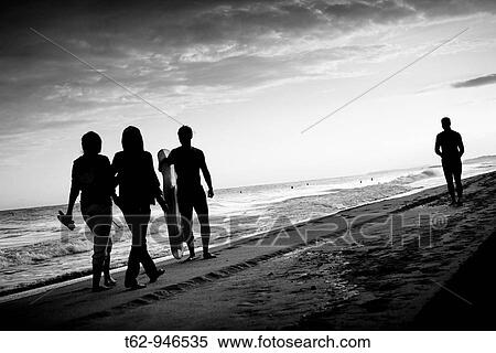 Stock Photography - Silhouettes on the beach With friends and one alone. Fotosearch