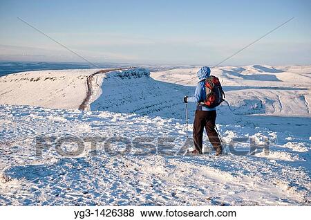 Stock Photo - Single female hiker of Snow covered summit of Pen Y Fan, Brecon Beacons national park, Wales. Fotosearch