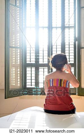 Single woman talking with mobile sitting on a bed. View Large Photo Image Stock Image - Single woman talking with mobile sitting on a bed.. Fotosearch