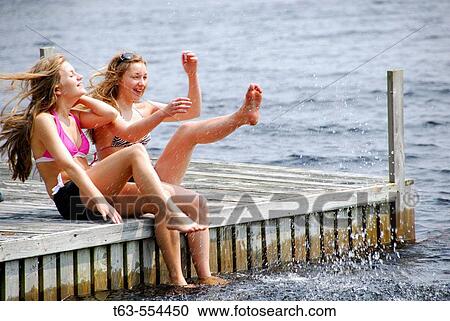 sisters 13 and 18 kicking up water while sitting on dock at lake View Large Photo Image Stock Image - sisters 13 and 18 kicking up water while sitting on dock at lake. Fotosearch