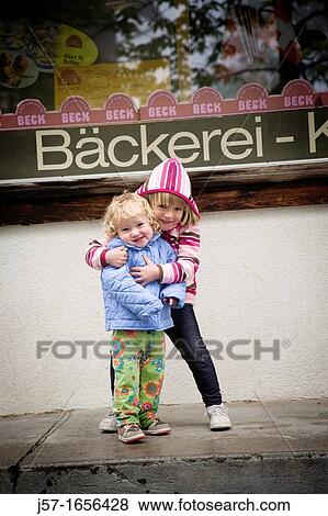 Sisters hugging and smiling at the camera in front of a backery in M? rren, Switzerland View Large Photo Image Stock Photo - Sisters hugging and smiling at the camera in front of a backery in M? rren, Switzerland. Fotosearch