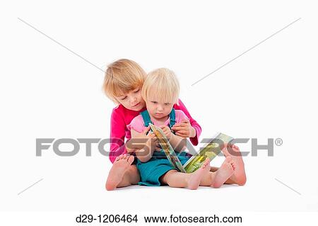 sisters looking at chidren's book - isolated on white View Large Photo Image Picture - sisters looking at chidren's book - isolated on white. Fotosearch