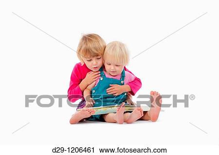 Stock Image - sisters looking at chidren's book - isolated on white. Fotosearch