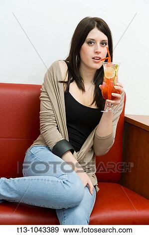 Sitting on a Red sofa with a cocktail pretty young woman View Large Photo Image Stock Photo - Sitting on a Red sofa with a cocktail pretty young woman. Fotosearch