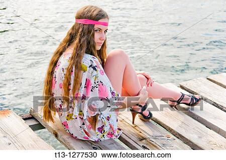 Sitting on a wooden pier young woman View Large Photo Image Stock Image - Sitting on a wooden pier young woman. Fotosearch