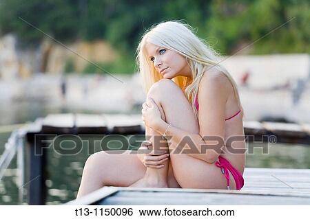 Sitting on a wooden wharf young woman with a long blonde hair View Large Photo Image Stock Photograph - Sitting on a wooden wharf young woman with a long blonde hair. Fotosearch