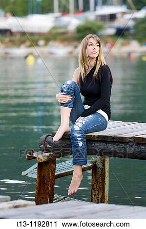 Sitting on an old wooden pier young woman View Large Photo Image Stock Image - Sitting on an old wooden pier young woman. Fotosearch