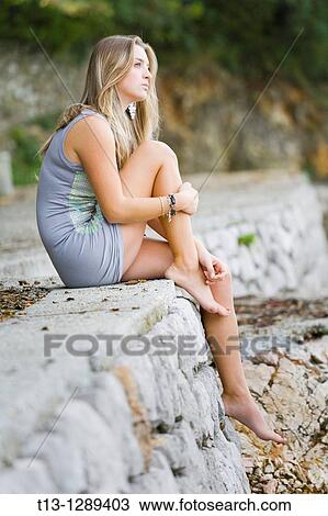 Stock Image - Sitting on the very edge young woman. Fotosearch