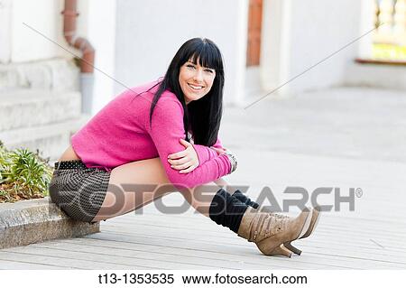 Stock Photography - Sitting very low on the street happy young woman. Fotosearch