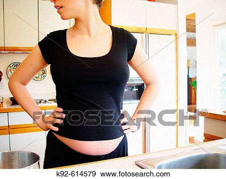 Six-month pregnant woman in her kitchen. View Large Photo Image Stock Photo - Six-month pregnant woman in her kitchen.. Fotosearch