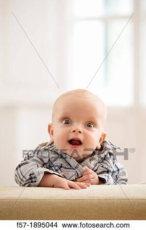 Six month year old baby holding on to the back of a sofa View Large Photo Image Picture - Six month year old baby holding on to the back of a sofa. Fotosearch