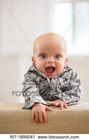 Six month year old baby holding on to the back of a sofa View Large Photo Image Stock Image - Six month year old baby holding on to the back of a sofa. Fotosearch