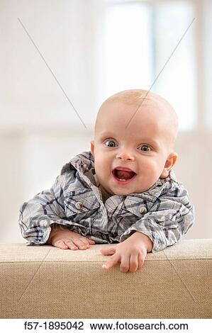 Six month year old baby holding on to the back of a sofa View Large Photo Image Stock Image - Six month year old baby holding on to the back of a sofa. Fotosearch